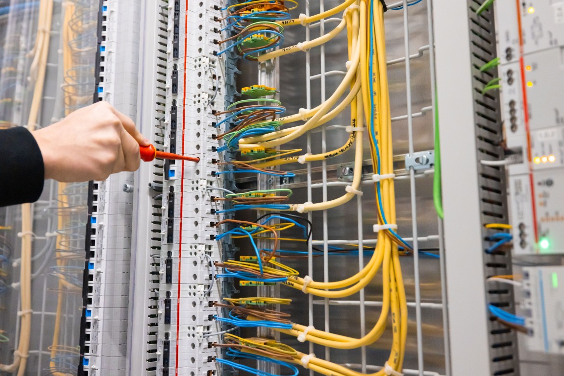 Hand mit Schraubenzieher im Elektroverteiler