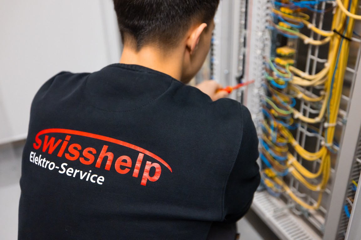 Swisshelp-Techniker arbeitet konzentriert am Schaltschrank