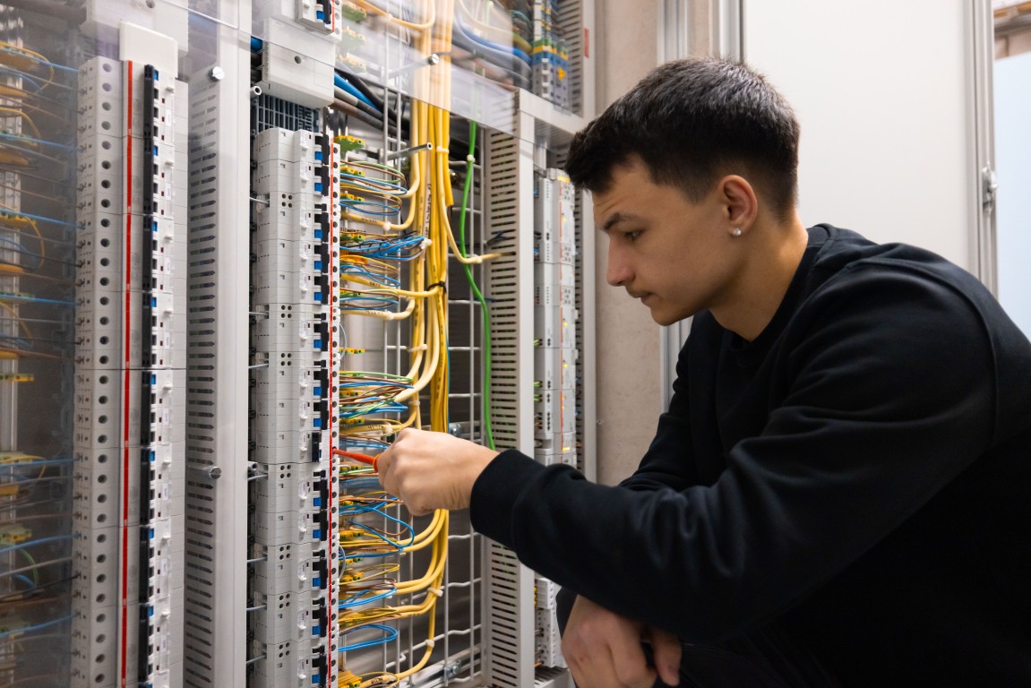 Junger Swisshelp Elektriker arbeitet am Verteiler mit dichten Steueradern in Schlieren