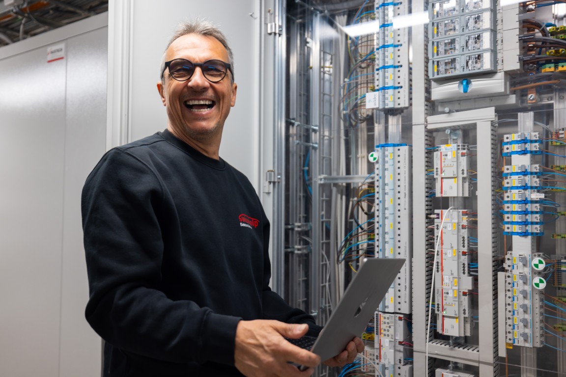 Monteur von Swisshelp Elektro prüft die Anlage mit dem Laptop im Schrankraum