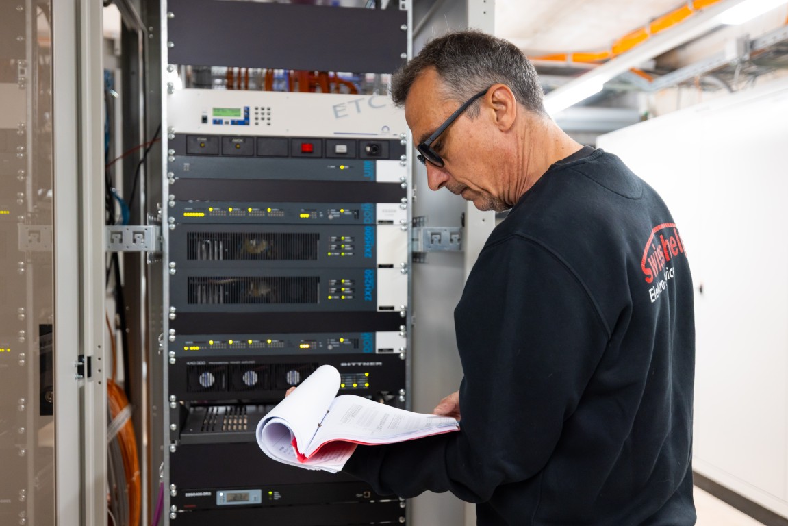 Swisshelp Monteur prüft die Anlage im Bürohaus gegen den Installationsplan