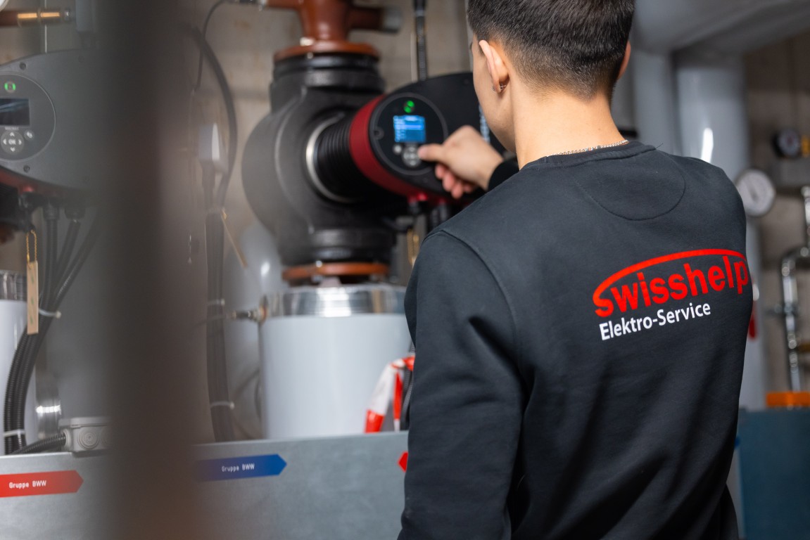 Monteur von Swisshelp Elektro prüft die Steuerung im Technikraum eines Mehrfamilienhauses