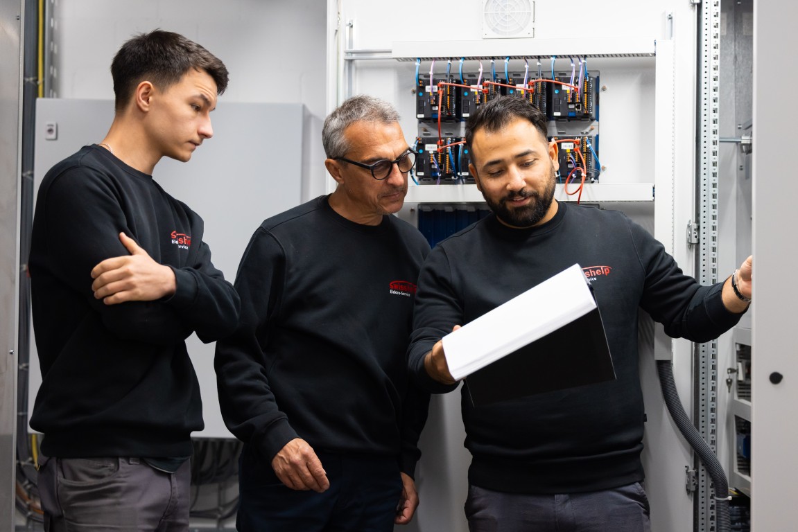 Team von Swisshelp Elektro arbeitet mit Laptop am offenen Schaltschrank