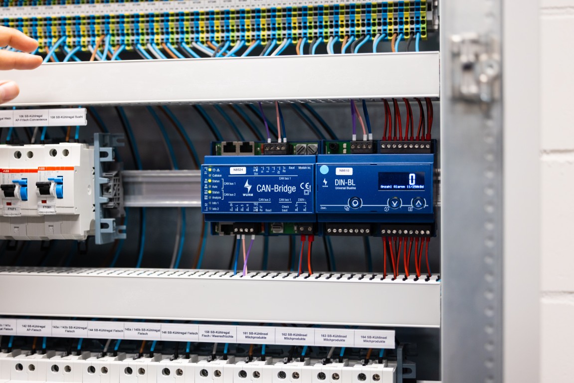 Nahaufnahme eines DIN-Controllers mit KNX-Modulen und Sicherungen im Verteiler