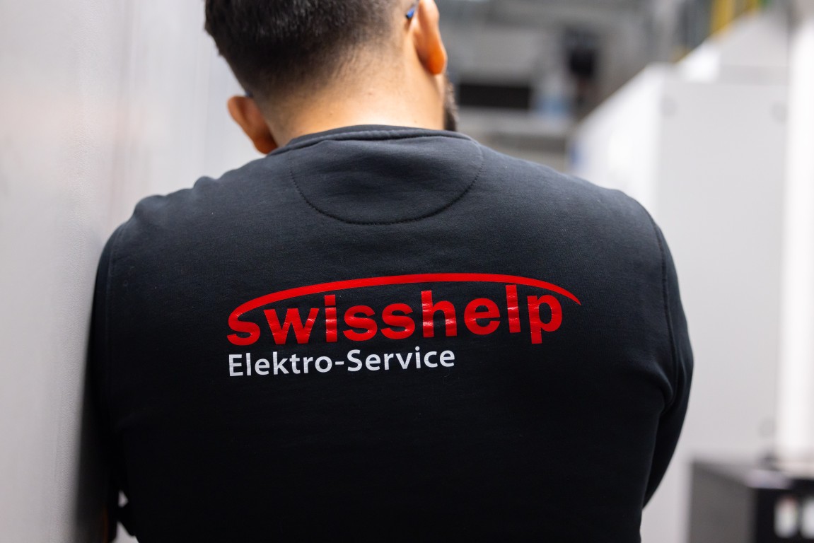 Swisshelp Monteur mit Firmenlogo im Einsatz an der Elektroanlage